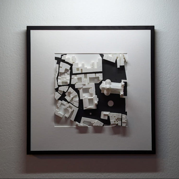 Framed Urband 3D black and white artwork illuminated by a wall-mounted light fixture.